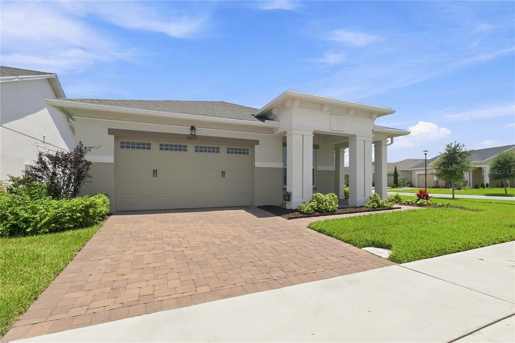 A single-story house with a beige stucco exterior, a two-car garage, and a paved driveway — 2699 MIDSWEET AVENUE, ST CLOUD, FL