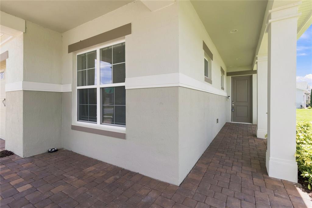 A covered entryway features a paver floor, a large window, and a solid front door — 2699 MIDSWEET AVENUE, ST CLOUD, FL