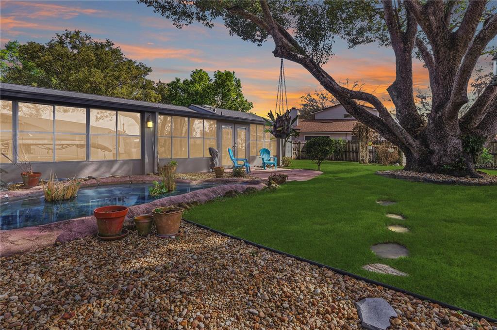A backyard features a small pond, a grassy lawn, a large tree, and a sunroom — 1307 ORTEGA STREET, WINTER SPRINGS, FL