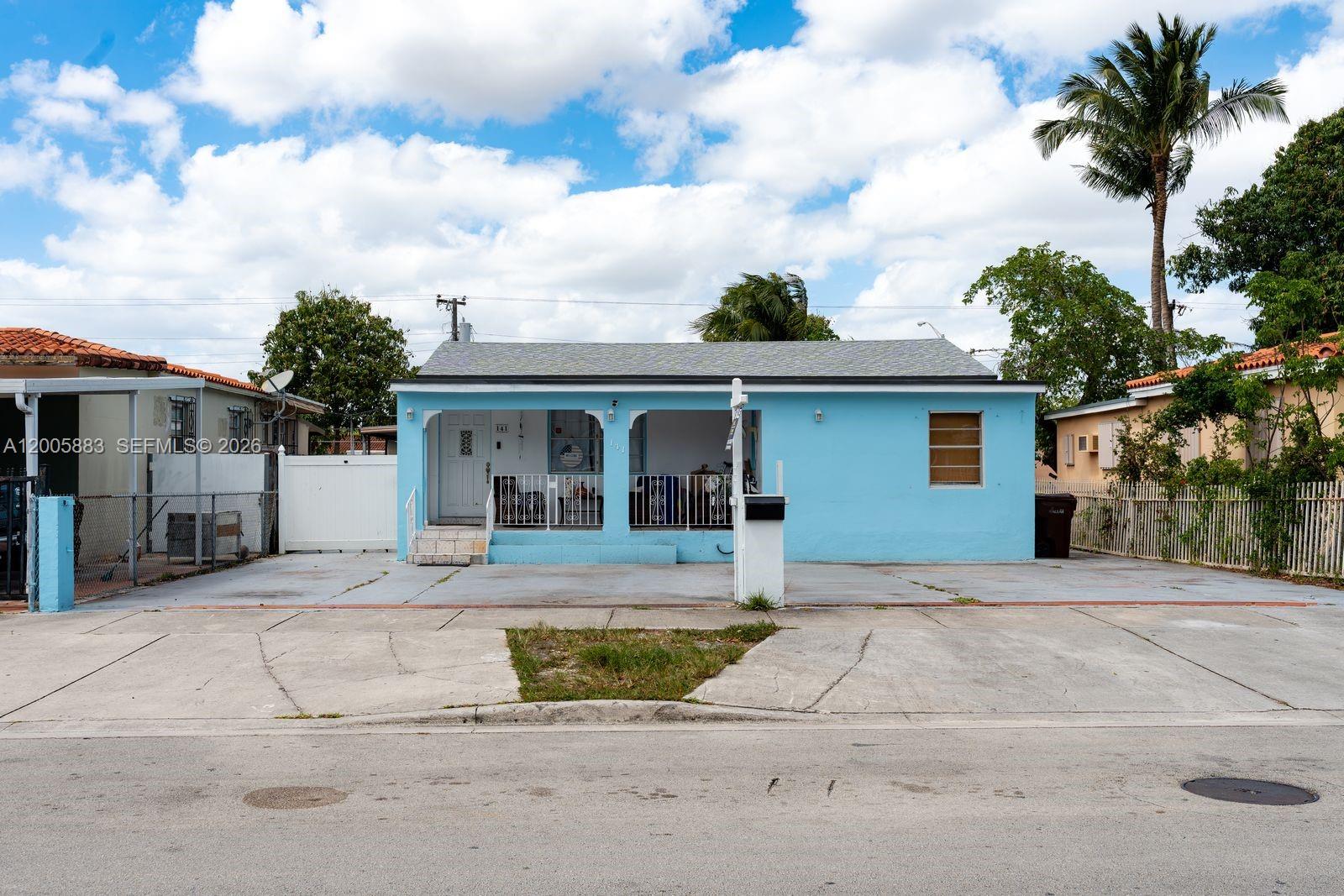 A light blue single-story house features a front porch, concrete driveway, and a palm tree — 141 E 16th St, Hialeah FL 33010, HIALEAH, FL