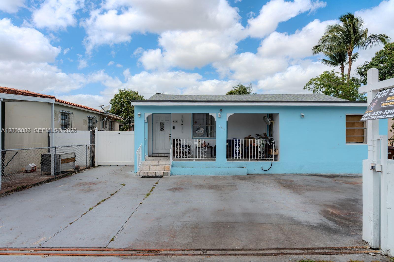 A light blue single-story house features a front porch with white railings and a driveway — 141 E 16th St, Hialeah FL 33010, HIALEAH, FL
