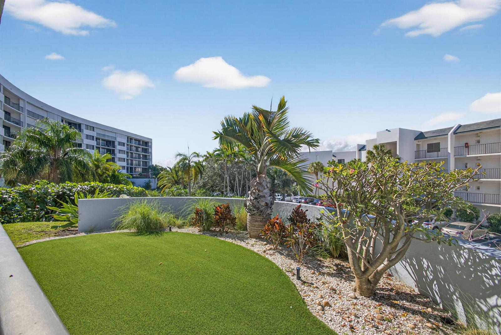 A landscaped terrace features artificial turf, a palm tree, and views of surrounding apartment buildings — 1300 Highway A1a Highway # 119, Jupiter FL 33477, JUPITER, FL