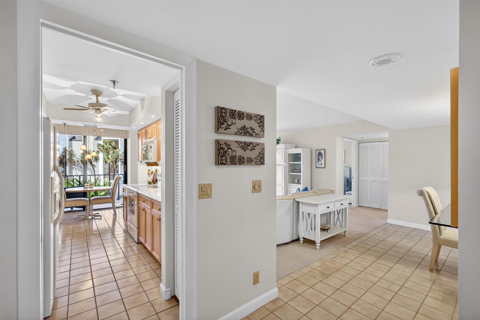 A view from a tiled hallway into a kitchen and a carpeted living area — 1300 Highway A1a Highway # 119, Jupiter FL 33477, JUPITER, FL