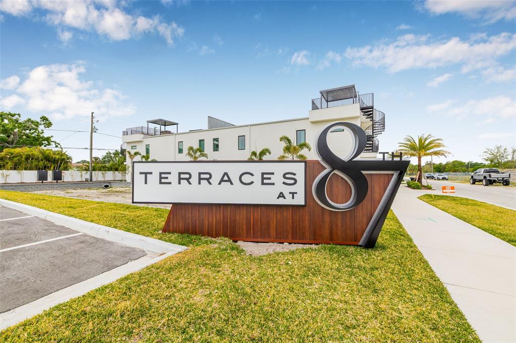 A modern monument sign for Terraces at 87th stands in front of a multi-story building — 460 87TH AVENUE NORTH, ST PETERSBURG, FL