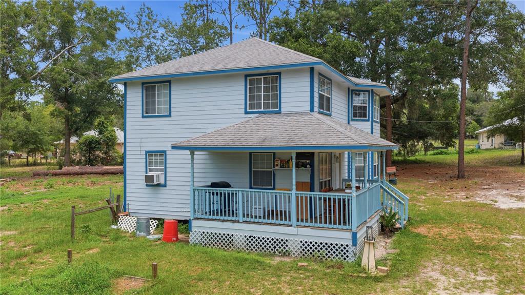 A two-story light blue house with a wrap-around porch and lattice skirting — 6870 SW 206TH AVENUE, DUNNELLON, FL