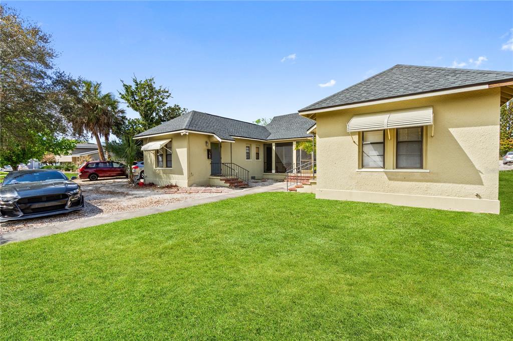A tan stucco house with a dark shingled roof sits behind a green lawn — 315 RIDGE MANOR DRIVE, LAKE WALES, FL