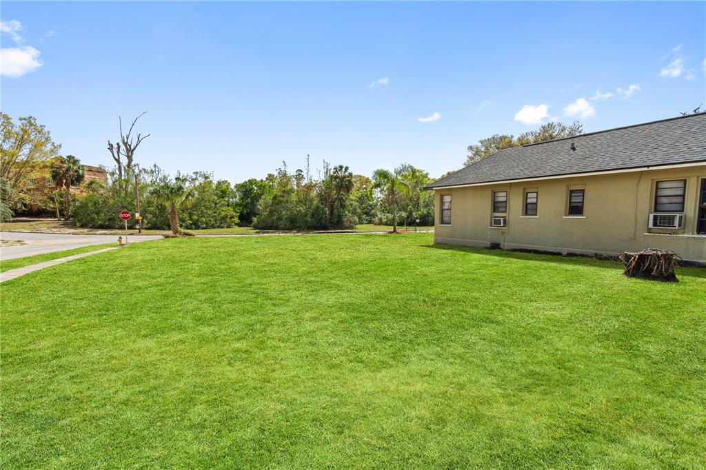 A grassy side yard next to a tan house with a stop sign in the distance — 315 RIDGE MANOR DRIVE, LAKE WALES, FL