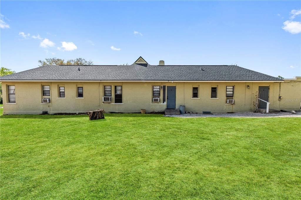 A long, single-story house with a tan stucco exterior and a dark shingled roof — 315 RIDGE MANOR DRIVE, LAKE WALES, FL