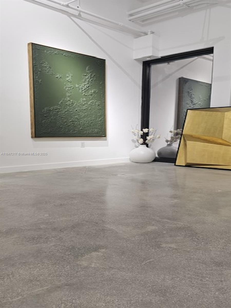 A minimalist room features a textured green painting, a large mirror, and concrete flooring — 136 NW 26th St, Miami FL 33127, MIAMI, FL