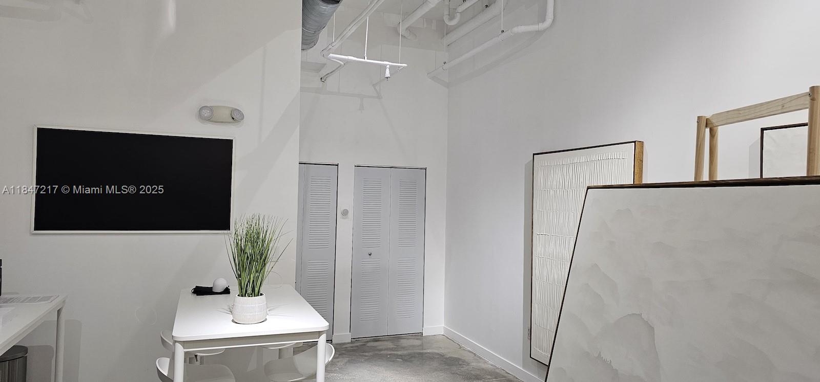 A modern office space features white walls, exposed ceiling pipes, and a white table — 136 NW 26th St, Miami FL 33127, MIAMI, FL