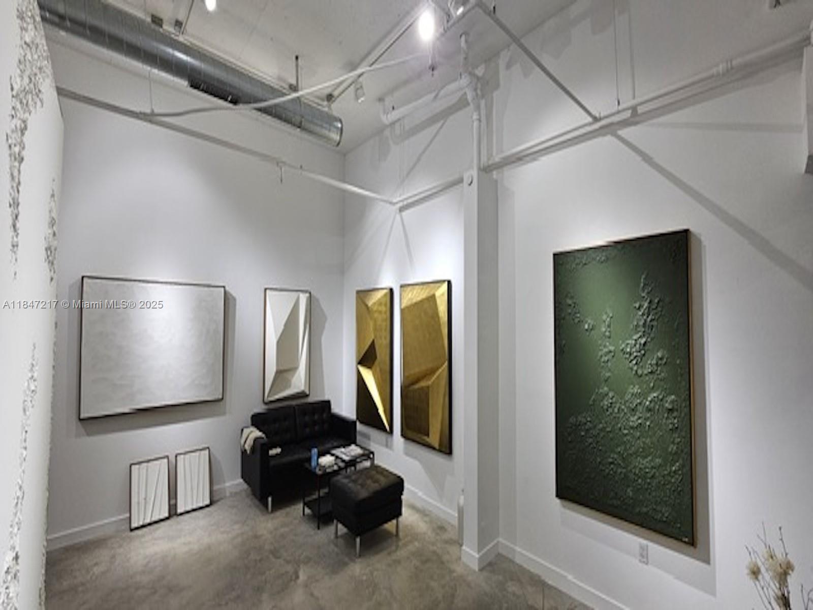 A modern gallery-style room features white walls, exposed industrial ductwork, concrete floors, and various artworks — 136 NW 26th St, Miami FL 33127, MIAMI, FL
