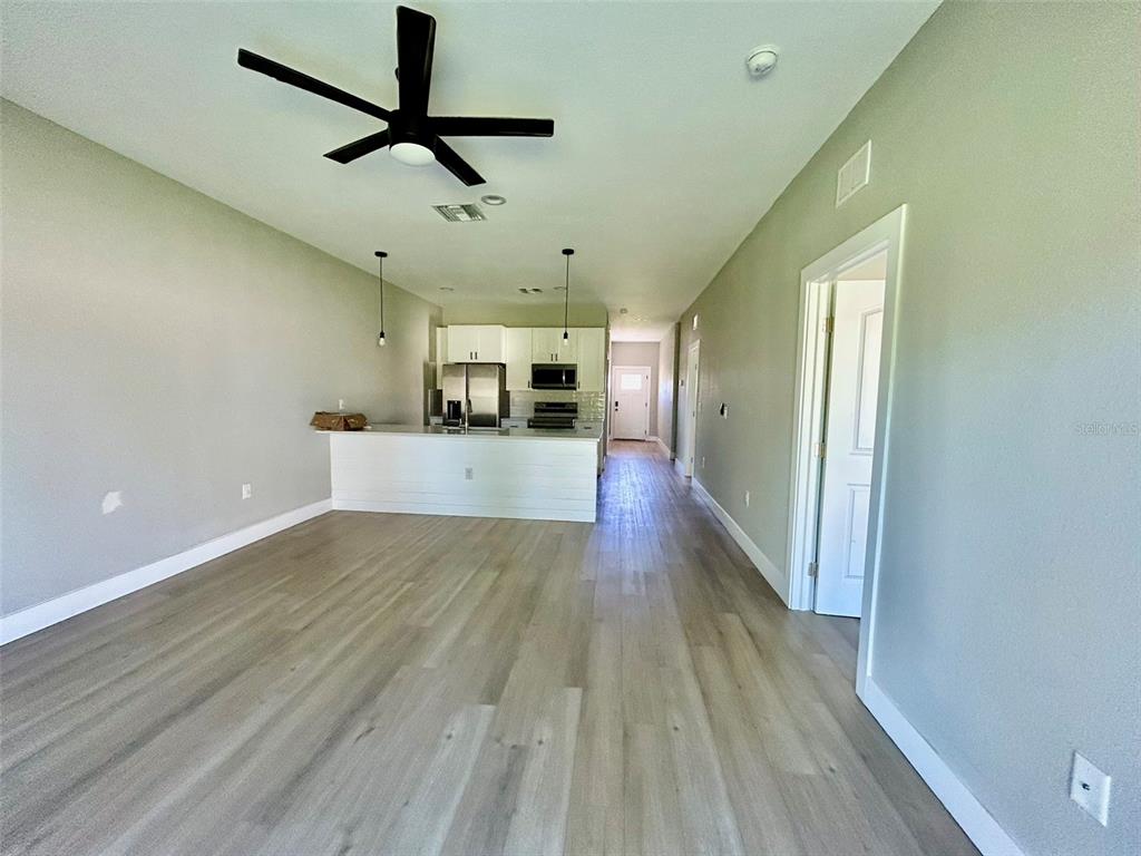 An open-concept living area features light wood flooring, a ceiling fan, and a white kitchen — 12552 BUFFING ROAD, PORT CHARLOTTE, FL