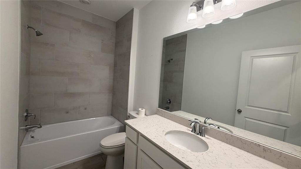A bathroom features a white vanity with a quartz countertop, a mirror, and a tub-shower — 19725 SW 79TH PLACE, DUNNELLON, FL