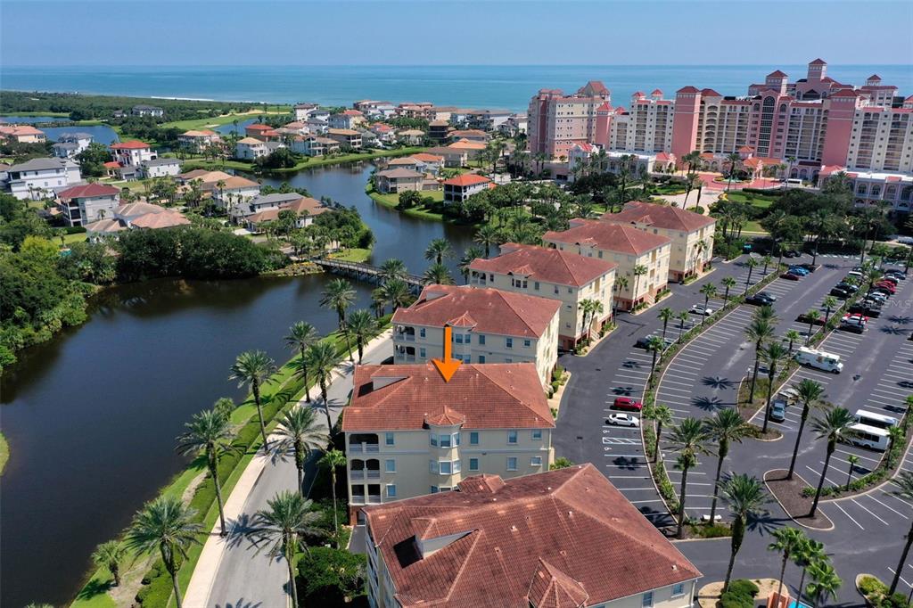 An aerial view shows multi-story residential buildings with red tile roofs near a coastal waterway — 55 OCEAN CREST WAY UNIT 922, PALM COAST, FL