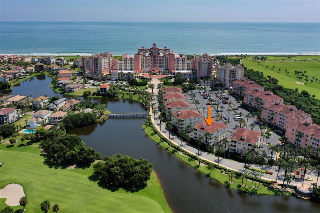 An aerial view shows a multi-story residential building marked with an orange arrow near water — 55 OCEAN CREST WAY UNIT 922, PALM COAST, FL