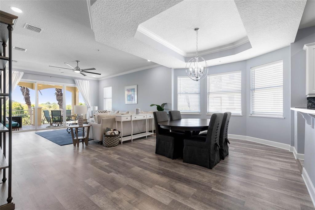An open-concept living and dining area features light gray walls, wood-look flooring, and a balcony — 55 OCEAN CREST WAY UNIT 922, PALM COAST, FL