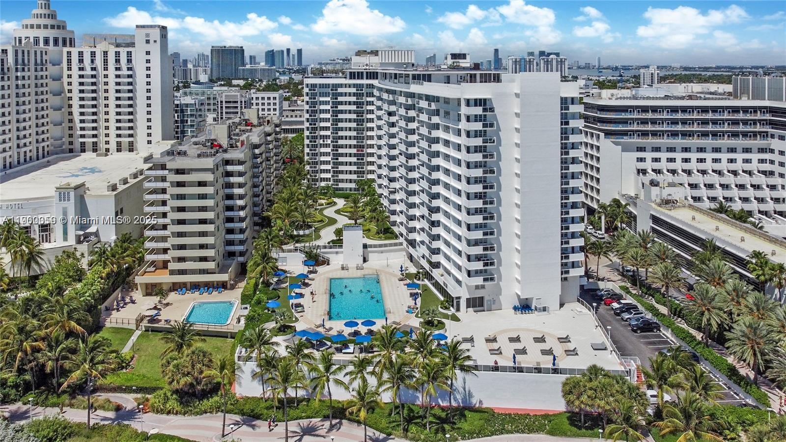 An aerial view of a multi-story apartment complex featuring two swimming pools and palm trees — 100 Lincoln Rd # 607, Miami Beach FL 33139, MIAMI BEACH, FL