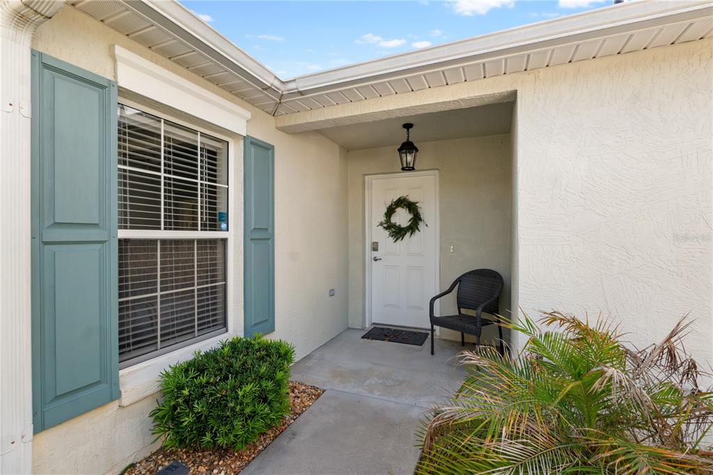 The exterior view shows a front entrance with a white door, blue shutters, and landscaping — 1666 SUMMERCHASE LOOP, THE VILLAGES, FL