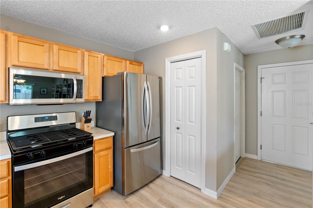 A kitchen features light wood cabinets, stainless steel appliances, and light-colored wood-look flooring — 1666 SUMMERCHASE LOOP, THE VILLAGES, FL