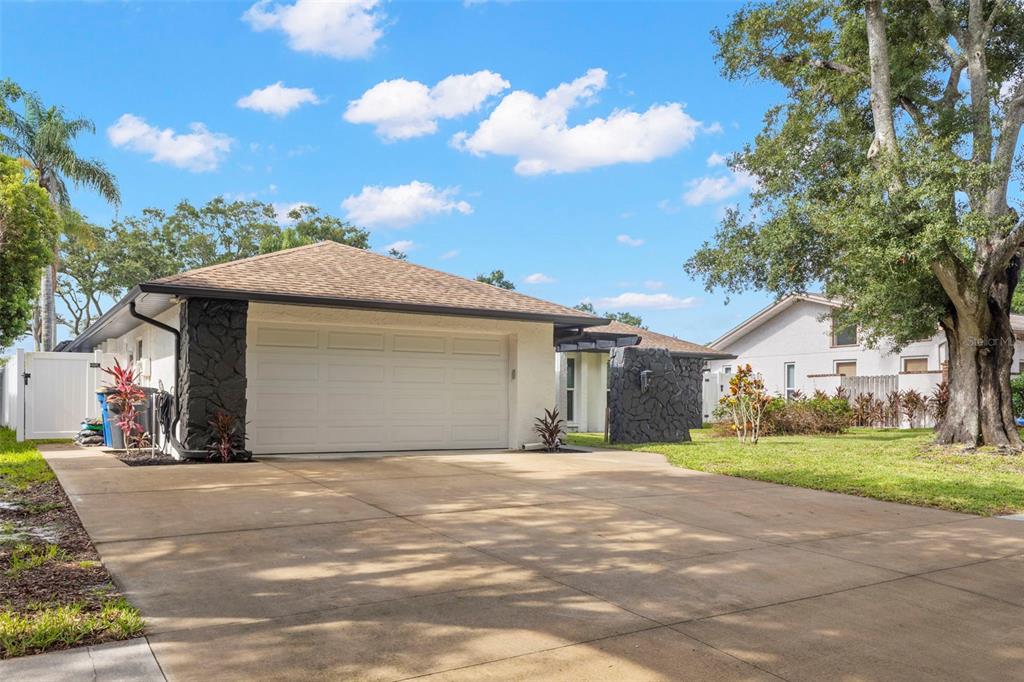 A single-story house with a white stucco exterior, dark stone accents, and a concrete driveway — 3097 HAVERFORD DRIVE, CLEARWATER, FL