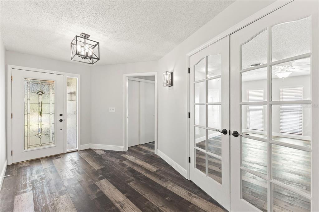 An entryway features wood-look flooring, a glass-paneled front door, and French doors leading to another room — 3097 HAVERFORD DRIVE, CLEARWATER, FL