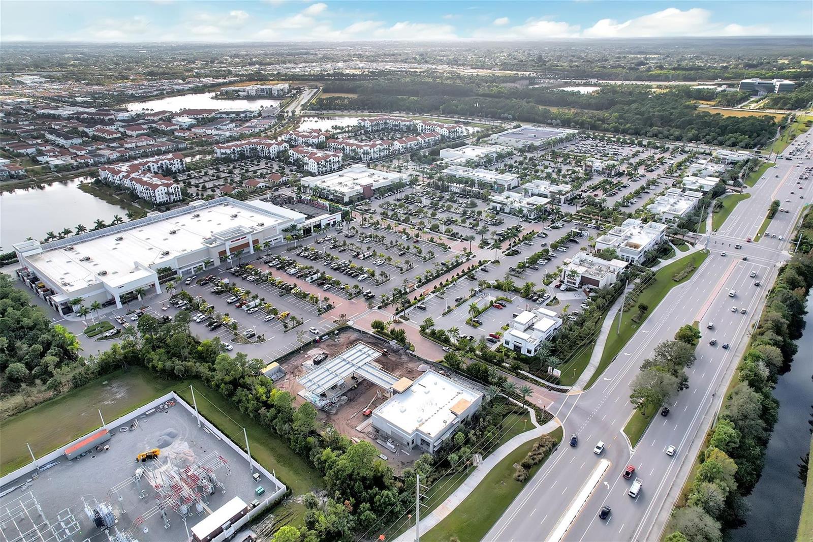 An aerial view shows a commercial shopping center with parking lots, surrounding roads, and buildings — 4941 E Bonsai Circle E # 209, Palm Beach Gardens FL 33418, PALM BEACH GARDENS, FL