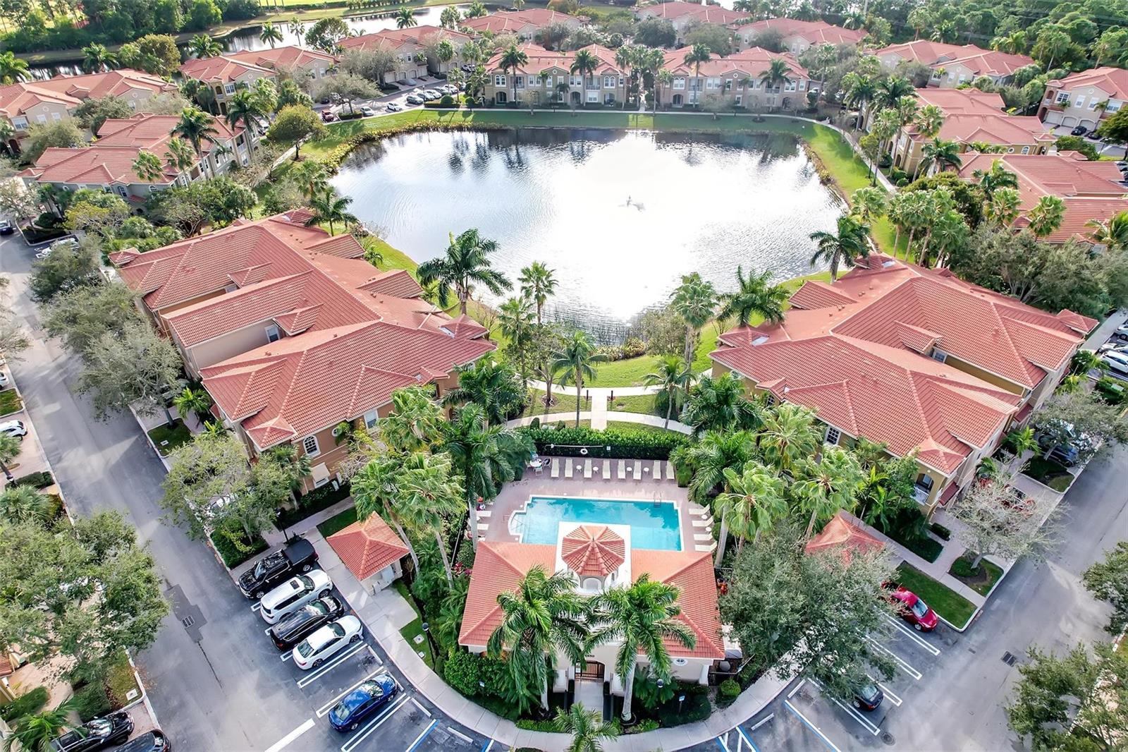 An aerial view shows a residential complex with a central pool and a large lake — 4941 E Bonsai Circle E # 209, Palm Beach Gardens FL 33418, PALM BEACH GARDENS, FL