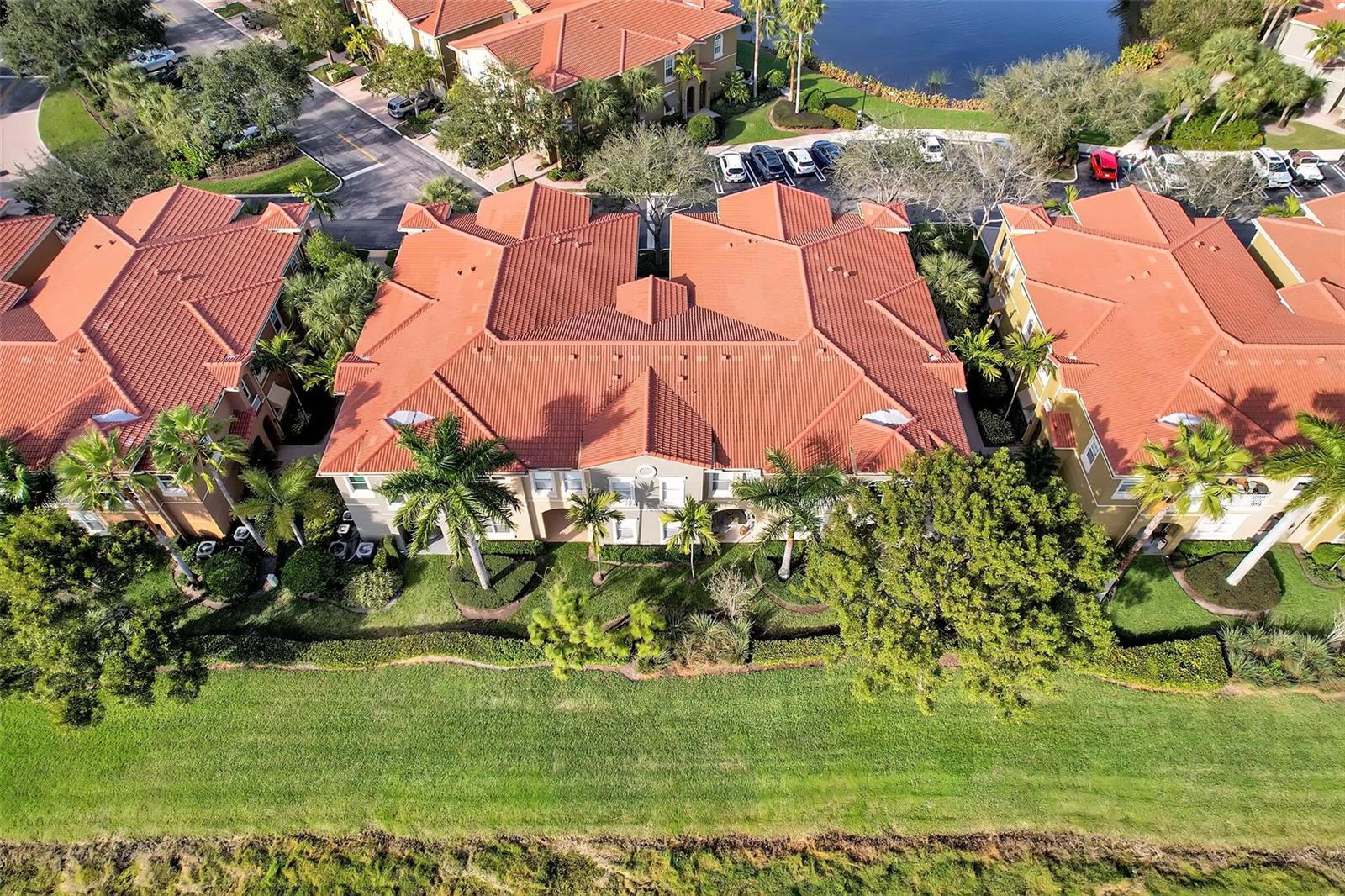 An aerial view shows three multi-story apartment buildings with orange tile roofs and palm trees — 4941 E Bonsai Circle E # 209, Palm Beach Gardens FL 33418, PALM BEACH GARDENS, FL