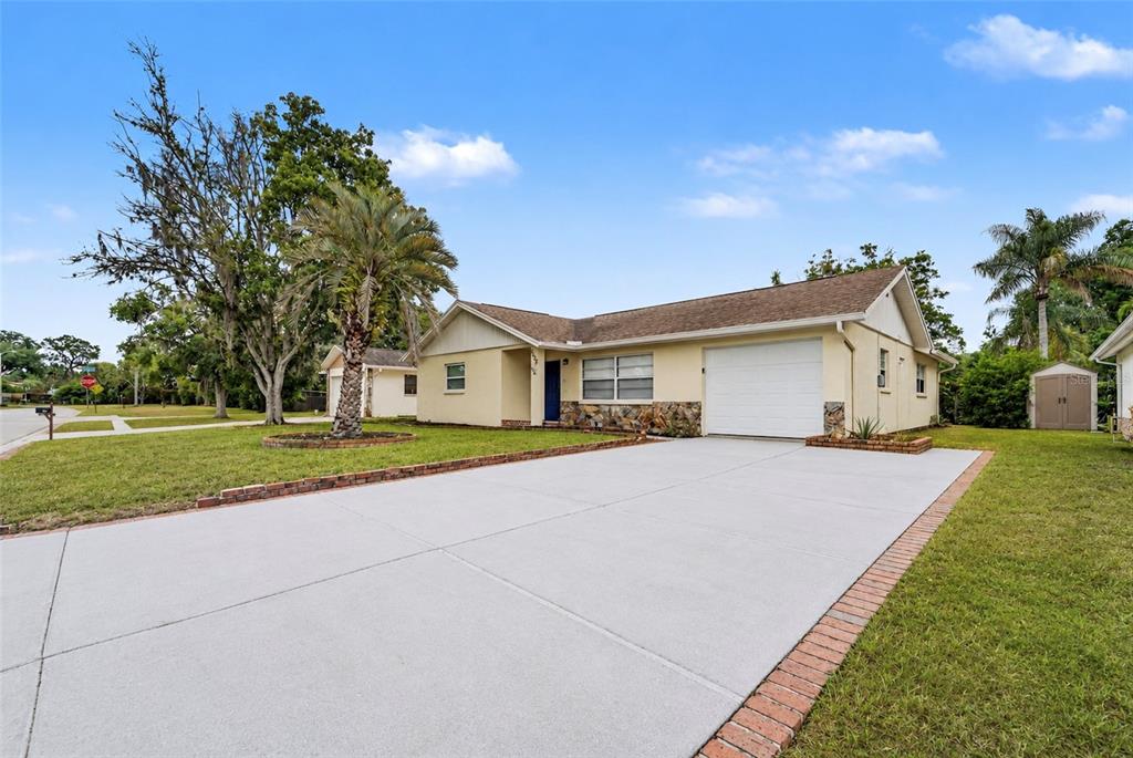 A single-story house with a light yellow exterior, stone accents, and a concrete driveway — 8332 FISHHAWK AVENUE, NEW PORT RICHEY, FL