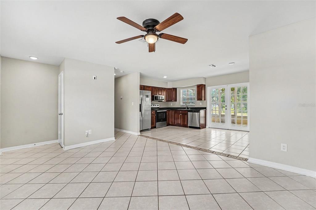 An open-concept kitchen and living area features tile flooring, dark wood cabinets, and stainless appliances — 8332 FISHHAWK AVENUE, NEW PORT RICHEY, FL