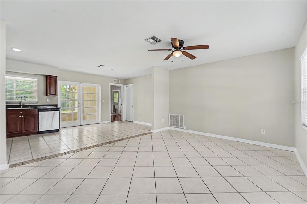 A room with light-colored tile flooring, a ceiling fan, and a small kitchen area — 8332 FISHHAWK AVENUE, NEW PORT RICHEY, FL
