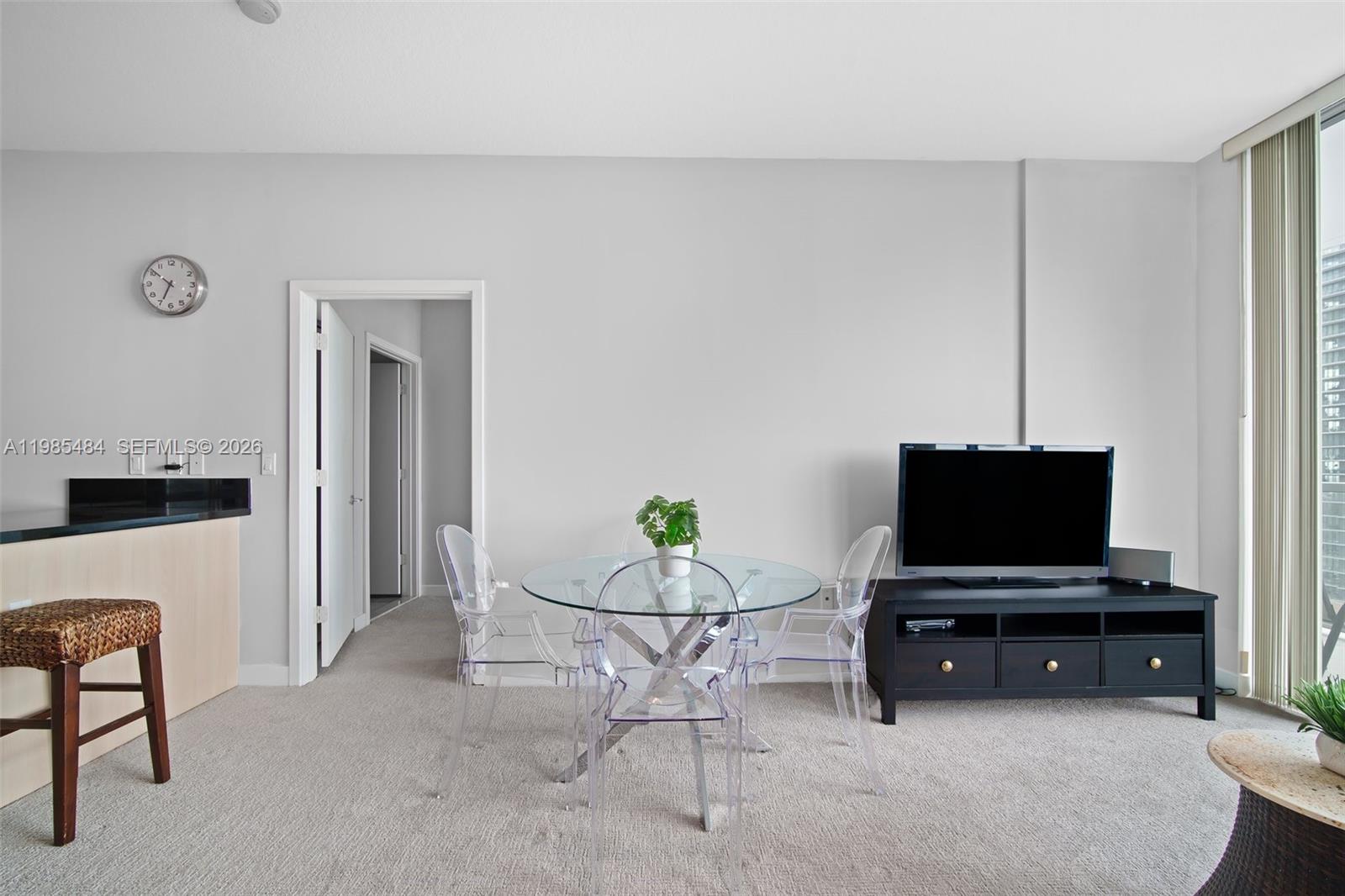 A dining area features a glass table with clear chairs and a black television console — 79 SW 12th St, Miami FL 33130, MIAMI, FL