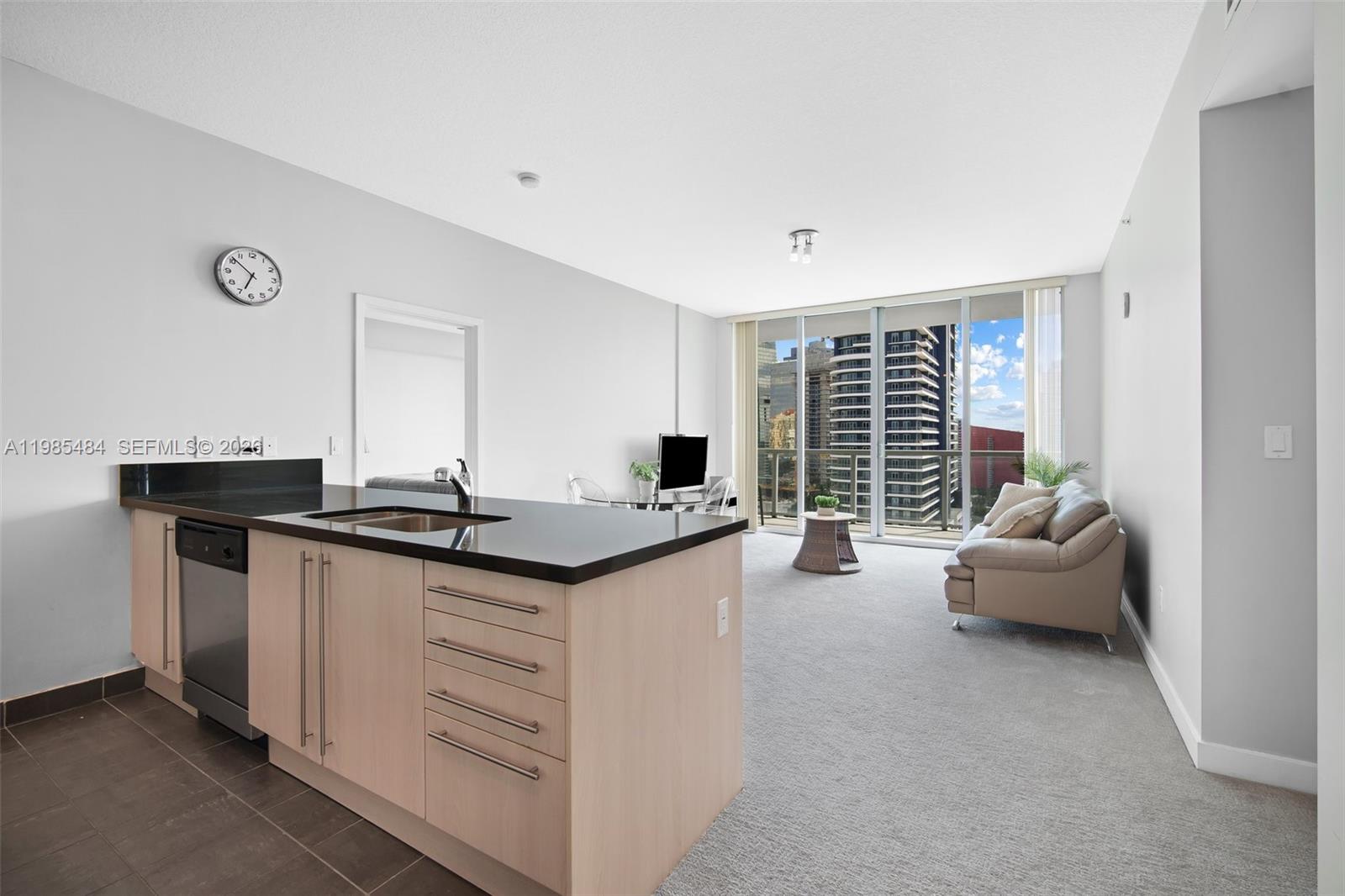 A modern apartment features an open-concept kitchen with light wood cabinets and a living area — 79 SW 12th St, Miami FL 33130, MIAMI, FL