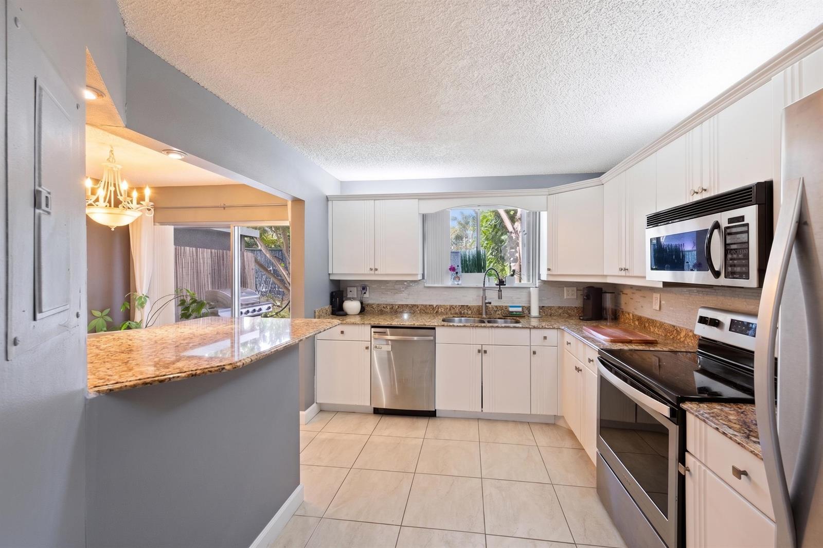 A kitchen with white cabinets, granite countertops, stainless steel appliances, and tile flooring — 1928 Discovery Circle E, Deerfield Beach FL 33442, DEERFIELD BEACH, FL