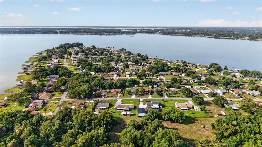 An aerial view shows a residential neighborhood situated on a peninsula extending into a lake — 5216 SYDNEY ROAD, FRUITLAND PARK, FL