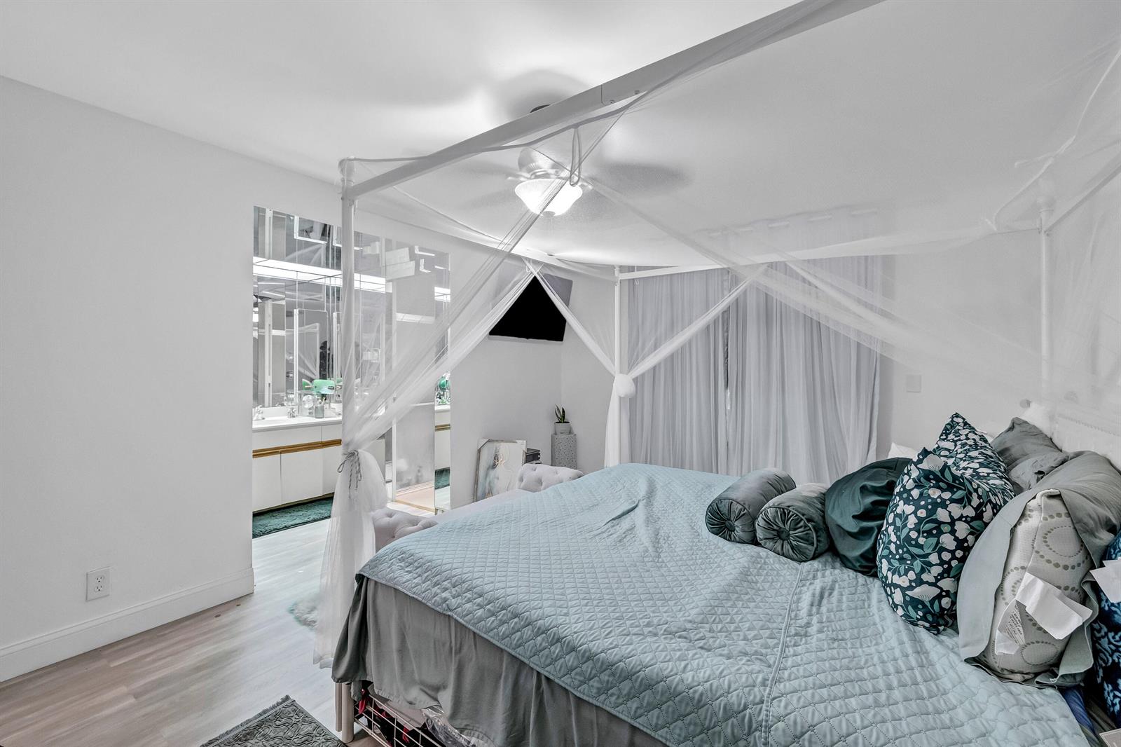 A bedroom features a canopy bed with white netting and an attached bathroom with mirrors — 6137 Rainbow Circle, FL 33463, FL