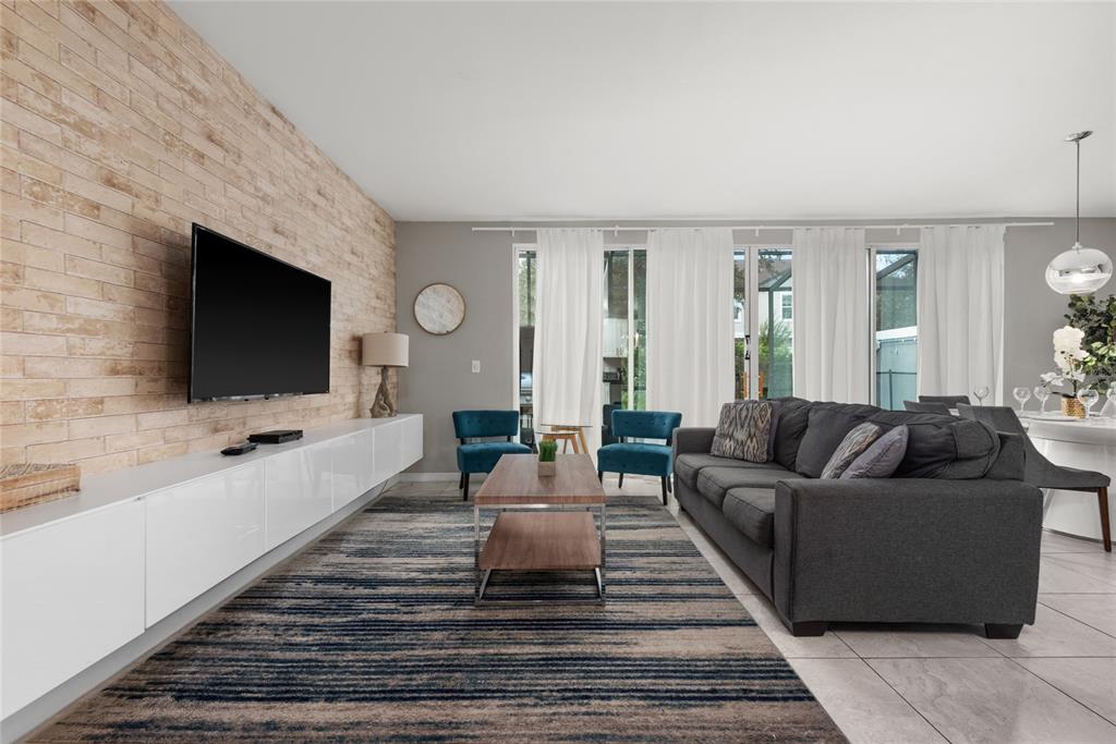 A living room features a brick accent wall, a white media console, and gray furniture — 4402 LE REVE COURT, KISSIMMEE, FL