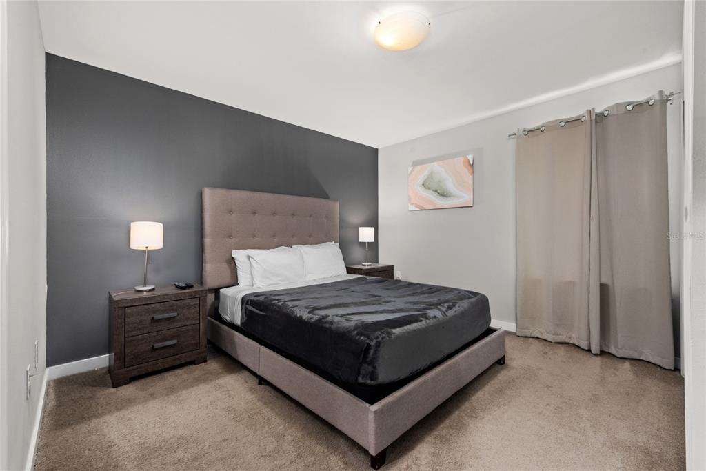 A bedroom features a gray accent wall, a tufted headboard, and beige curtains — 4402 LE REVE COURT, KISSIMMEE, FL