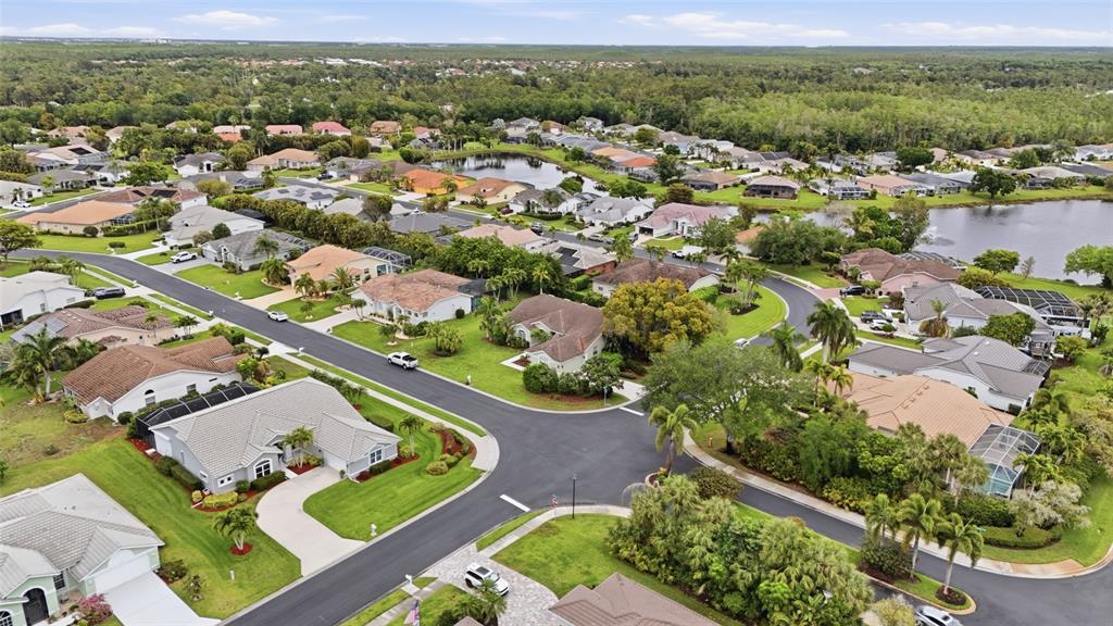An aerial view shows a suburban neighborhood with houses, paved streets, and a small lake — 12761 DRESDEN COURT, FORT MYERS, FL