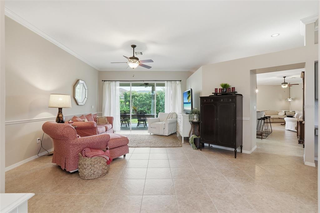 A living room with tile floors, a pink sofa, and a view of a patio — 12761 DRESDEN COURT, FORT MYERS, FL