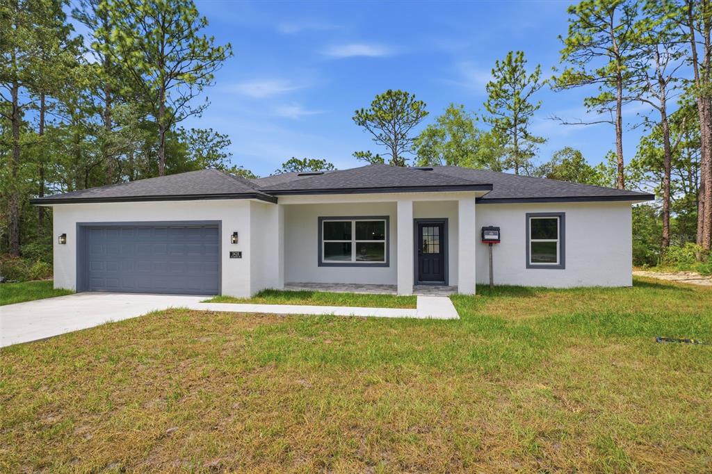 A single-story white house with a gray garage door and a covered front porch — 3428 W CUSHION DRIVE, CITRUS SPRINGS, FL
