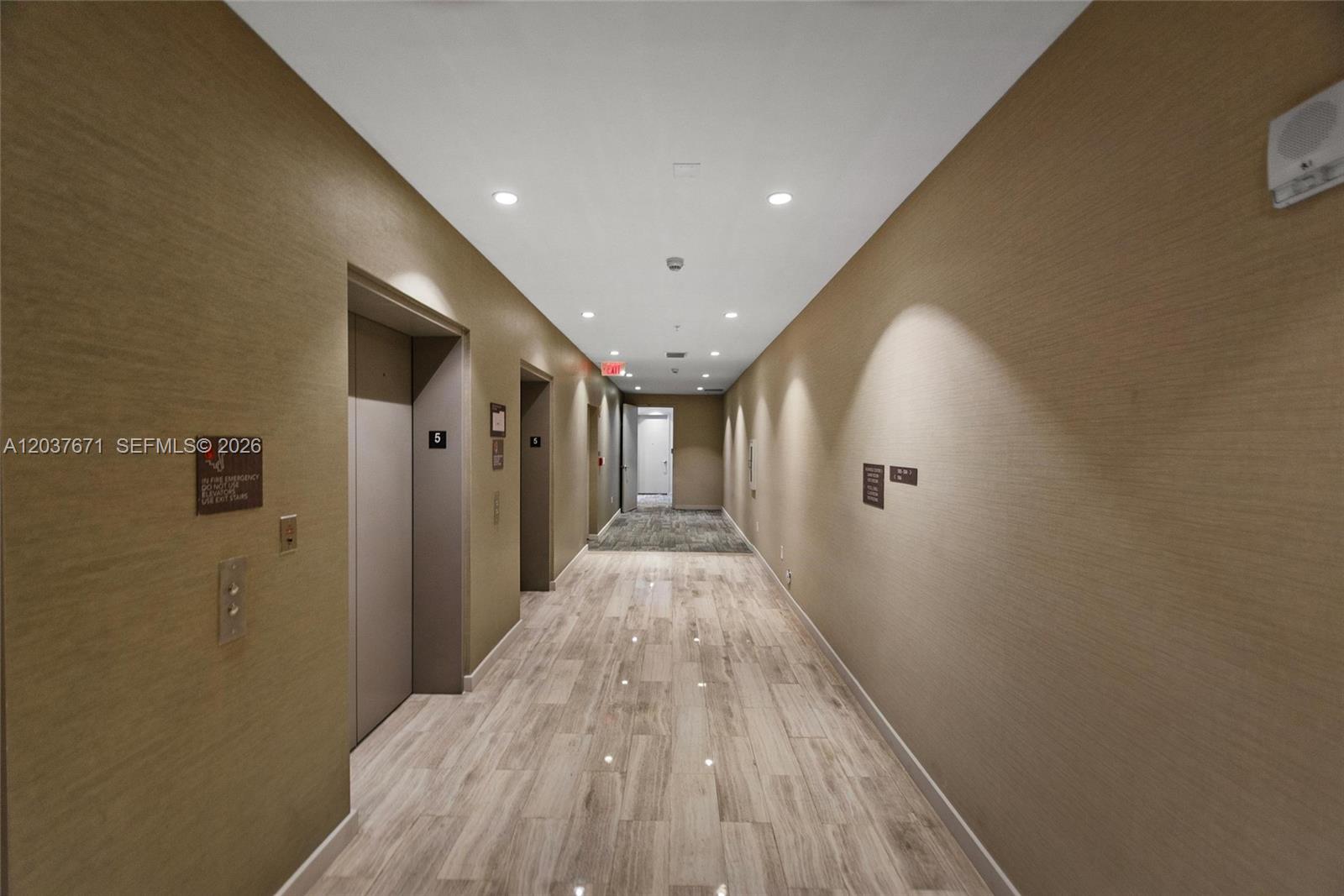 A hallway features light wood-look tile flooring, beige textured walls, and two elevator doors — 1010 SW 2nd Ave # 1709, Miami FL 33130, MIAMI, FL