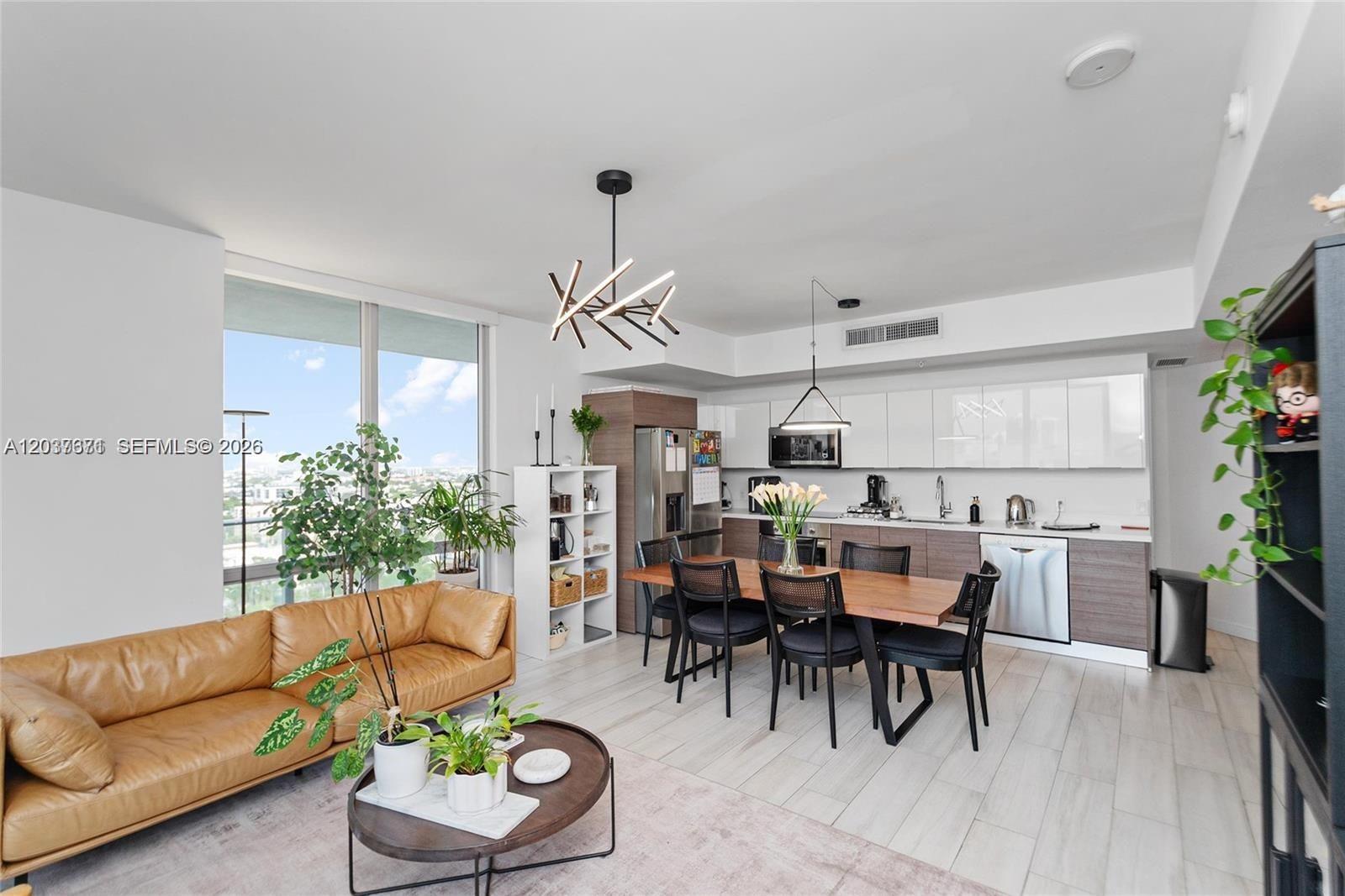 A modern open-concept living and dining area features a leather sofa, wood table, and kitchen — 1010 SW 2nd Ave # 1709, Miami FL 33130, MIAMI, FL