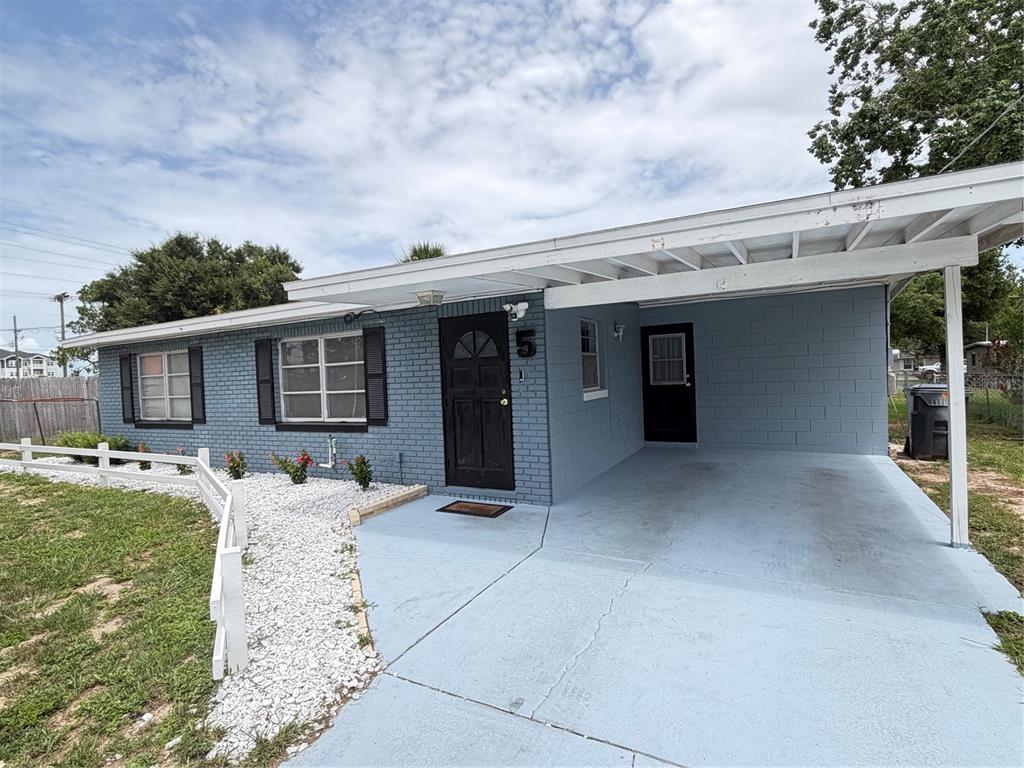 A blue, single-story house with a carport, white fence, and white gravel landscaping — 5 MOONLIGHT LANE, WINTER HAVEN, FL