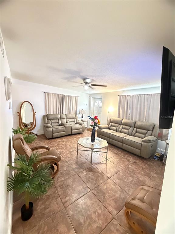 A living room features light-colored reclining sofas, a central coffee table, and tiled flooring — 5 MOONLIGHT LANE, WINTER HAVEN, FL