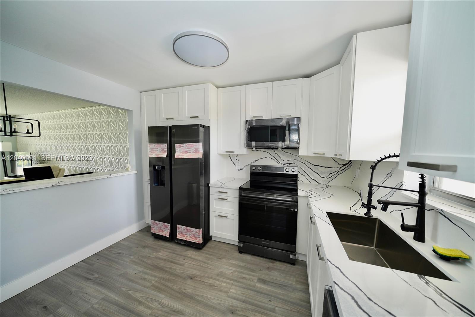 A kitchen features white cabinets, black appliances, and white countertops with bold black veining — 2541 Aragon Blvd # 305, Sunrise FL 33322, SUNRISE, FL