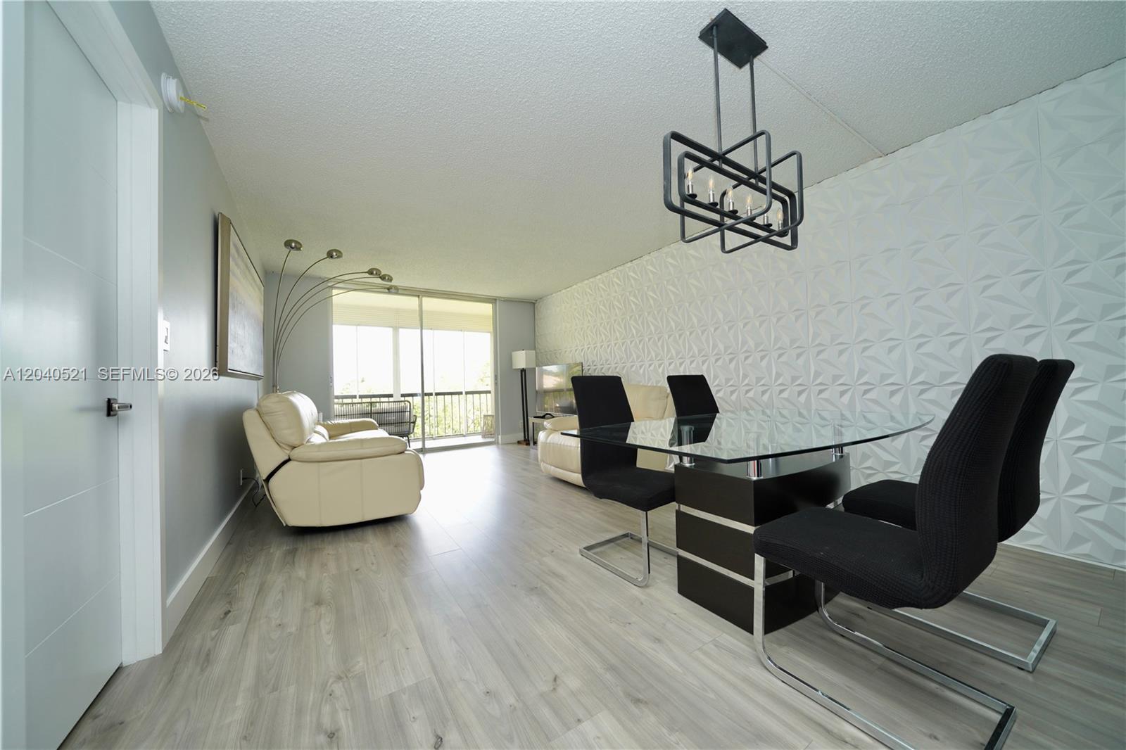 A dining and living area features a glass table, black chairs, and textured wall panels — 2541 Aragon Blvd # 305, Sunrise FL 33322, SUNRISE, FL