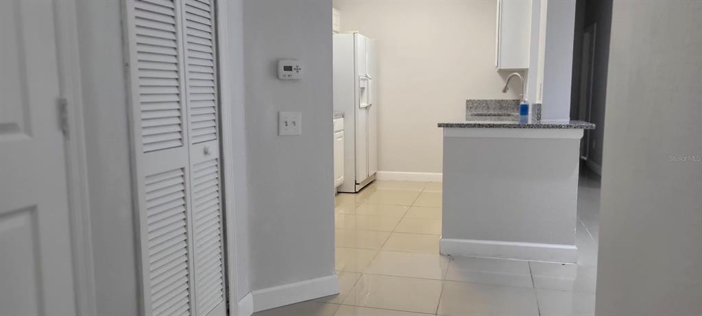 A view of a kitchen with tile floors, white cabinets, and a granite-topped breakfast bar — 7147 YACHT BASIN AVENUE UNIT 114, ORLANDO, FL