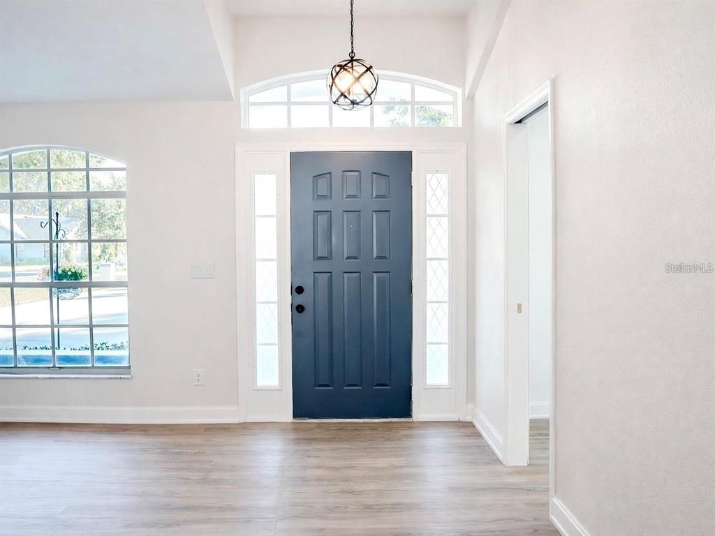 An entryway features a blue front door with sidelights, a transom window, and wood flooring — 10711 LAKE HILL DRIVE, CLERMONT, FL