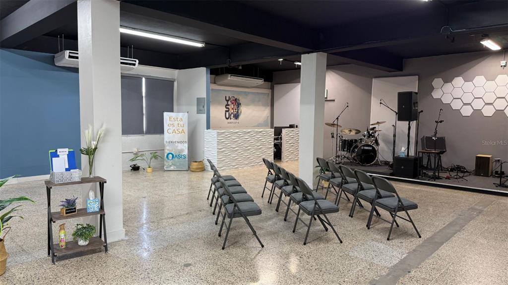 A room with rows of chairs, a small stage with musical instruments, and concrete floors — #6 CALLE HERMINO DIAZ NAVARRO, GUAYNABO, PR